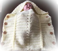 a baby wrapped in a crochet blanket with buttons on the bottom and inside