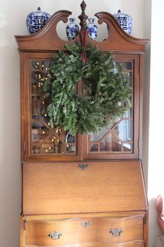 an old china cabinet with a wreath on top