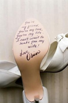 a pair of white shoes with writing on the soles and one has a handwritten message