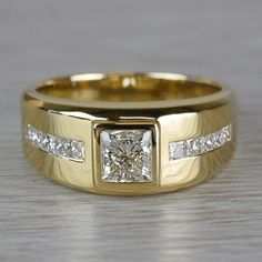 a yellow gold wedding ring with two princess cut diamonds on the side and channel set in the middle