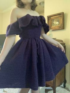 a woman in a purple dress is posing for the camera with her hands on her hips