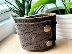 "I've made this wrapping cuff out of smooth leather with a black stitched design. Choose from a brown or black leather base. It has attached elastics that hook over two rivets so this cuff will adjust to fit most wrist sizes 6 to 7.5\" in circumference. The cuff is 2\" wide at the narrowest and 2.75\" at the widest end. This cuff is quite unique, I get lots of feedback comments such as: \"I have hard to fit wrists and it fits perfectly.\" \"The leather is so soft and feels great on my skin.\" \" Wrist Tattoo Cover Up, Third Anniversary, Modern Bracelets, Wide Bracelet, Simple Bracelets, Boho Leather, Unisex Bracelets, Recycled Leather, Leather Gifts