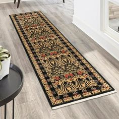 a black and gold runner rug on the floor next to a table with a plant