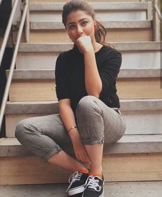 a woman sitting on the steps with her hand under her chin