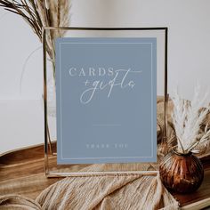 a blue card with the words cards and gifts on it next to some dried plants