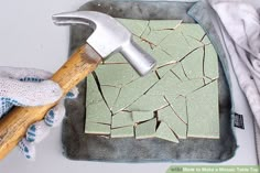 a hammer and some broken tiles on a table