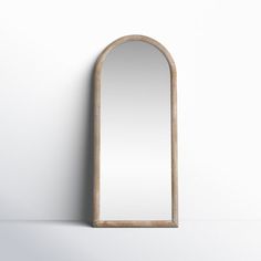 an arched wooden mirror hanging on the wall