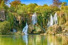 the waterfall is surrounded by trees and water