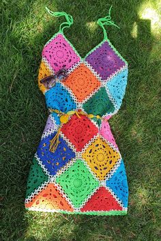 a colorful crocheted dress laying on the grass