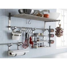 a kitchen with blue tiles and stainless steel shelving, hanging utensils on the wall