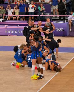 a group of women standing on top of a volleyball court in front of a crowd