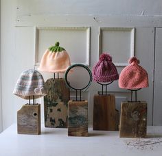 five knitted hats are on wooden blocks in front of a white door and window