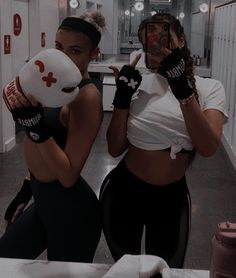 two women in black and white outfits holding up their hands