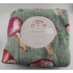 a green and pink blanket with mushrooms printed on it's sides, in front of a white background