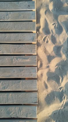 a wooden bench sitting on top of a sandy beach