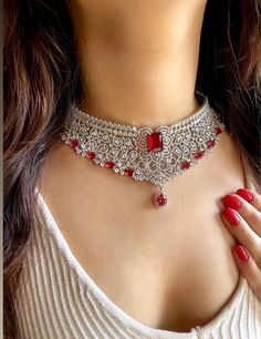 Gorgeous fine quality lab diamonds studded in white gold rhodium plating with  Red stones and high quality zirconia. This beautiful choker  set can be paired well with any outfit, be it ethnic or indo-western. What's more, it shines and blings in the right light! For any queries, please feel free to contact us. Happy shopping!  Comes with matching earrings. AAA quality cubic zirconia used. Highest quality and craftsmanship Item includes: Necklace, Earrings and Maangtika Necklace length 14 inches Diamond Choker Necklace For Wedding, White Gold Diamond Choker For Wedding, Red Hand-set American Diamond Jewelry, Cubic Zirconia Bridal Choker For Wedding, Hand Set Cubic Zirconia Choker Necklace, Hand-set Cubic Zirconia Choker Necklace, White Gold Wedding Choker Jewelry, Red Cubic Zirconia Diamond Necklace For Wedding, Dazzling Ruby Bridal Necklace In Diamond White