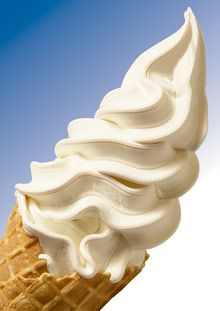 an ice cream cone with white icing on it's tip and blue sky in the background