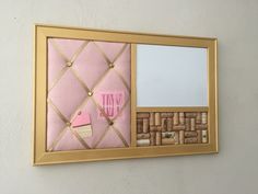 a pink and gold framed mirror with corks attached to the wall next to it