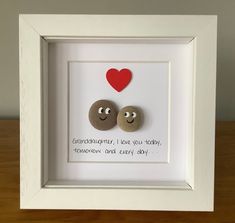 two rocks in a white frame with a red heart