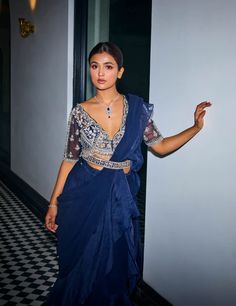 Indulge in ethereal charm with this midnight blue georgette and organza ruffle sari ensemble! Cascading ruffles crafted from georgette and organza create a captivating silhouette. The hand-embroidered v-neck scalloped blouse adds a touch of sophistication, enhanced by tassel detailing at the waist. Complete your look with a matching hand-embroidered belt for added flair. Bollywood Style Ruffled Organza Pre-draped Saree, Elegant Evening Lehenga With Ruffles, Elegant Ruffled Lehenga For Evening, Blue Georgette Pre-draped Saree For Evening, Elegant Blue Pre-draped Saree For Festive Occasions, Blue Ruffled Pre-draped Saree For Party, Festive Blue Ruffled Sets, Fusion Style Party Saree With Traditional Drape, Blue Ruffled Sets For Reception