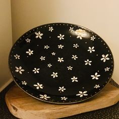 a black and white plate sitting on top of a wooden stand next to a wall