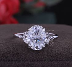 an oval cut diamond ring on top of a cushion