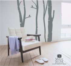 a white chair sitting in front of a wall with trees on it's side