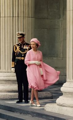 a man in uniform stands next to a woman in a pink dress and hat on steps