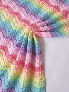 a multicolored crocheted blanket laying on top of a bed