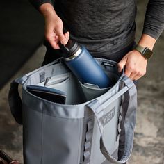 a person holding a gray bag with a water bottle in it