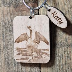 a wooden keychain with an image of a bird on it's back