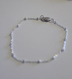 Dainty sterling silver bracelet made from a dainty cable chain with sterling silver beads. Finished with a sterling silver clasp and jump rings. Looks classy all on it's own or layer it with other bracelets. Different sizes are available at check out. All jewelry comes ready for gift giving. Everyday Chain Bracelet With Round Beads, Silver Dainty Bracelet With Extender, Dainty Silver Bracelet With Extender, Minimalist Satellite Chain Bracelet With Round Beads, Classic Adjustable Satellite Chain Bracelet, Minimalist Silver Chain Bracelet With Extender, Elegant Sterling Silver Bracelet With Extender For Everyday, Elegant Silver Beaded Bracelets With Delicate Chain, Elegant Silver Beaded Bracelet With Delicate Chain