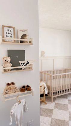 a baby's room with white walls and wooden shelves