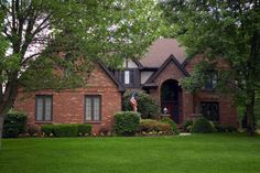 a brick house with an american flag in the front yard