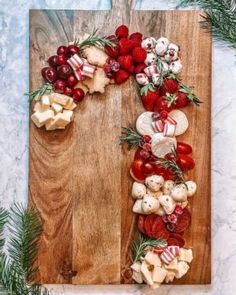 a christmas wreath made out of cheeses and cherries on a wooden cutting board