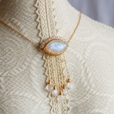 Crafted from a beautiful Marquise Rainbow Moonstone, this pendant has been artfully designed with a delicate cable-chain, a secure spring clasp and extension, and is adorned with a halo of white Cubic and five ethereal Moonstone teardrop tassels in 14K gold filled. In strong light, the main stone glimmers like the moon itself! The pictures do not adequately convey the exclusive beauty of this one-of-a-kind piece from Artisan Made. An effortless yet sophisticated accessory, it's perfect for eleva White Moonstone Jewelry With Adjustable Chain, White Delicate Jewelry Gift, Adjustable Ethereal White Jewelry, White Ethereal Jewelry For Gifts, Witchy Whimsical, Rainbow Moonstone Crystal, Whimsical Jewelry, Artfully Designed, Moonstone Crystal