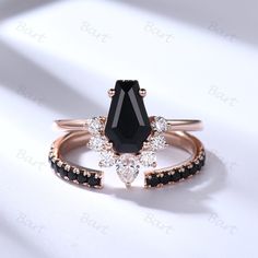 two rings with black and white stones on each side, one has a pear shaped diamond in the center