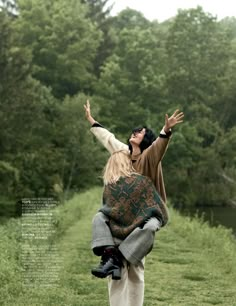 a man carrying a woman on his back in the middle of a field with trees