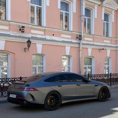 a grey sports car parked in front of a pink building