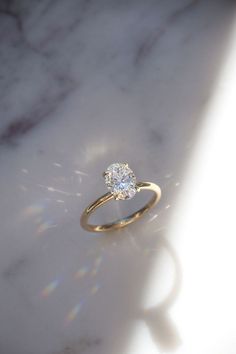 a diamond ring sitting on top of a white marble counter with the sun shining through it