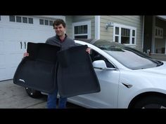 a man holding two bags in front of his car