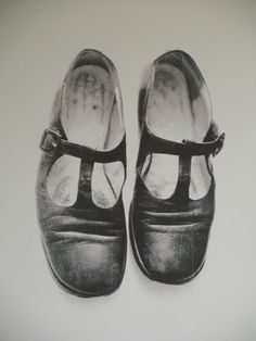 a pair of black shoes sitting on top of a white wall