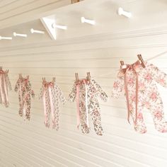 clothes hanging on a line with ribbons attached to them in front of a white wall