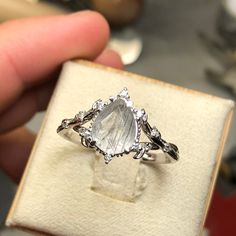 a person holding an engagement ring in their hand with a stone on it's side