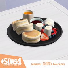 a black plate topped with pancakes, fruit and sauces on top of a white table