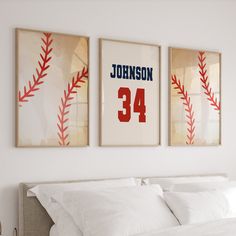 two framed baseball posters on the wall above a bed in a room with white sheets and pillows