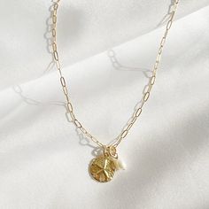 Natural AA freshwater pearl and sand dollar charms strung on 14k gold filled chain; adjustable. Charms are removable for versatility. Length: 16” + 2” extender Chain: 14k gold filled dainty paperclip chain with lobster clasp. Pearl: 4-5mm Sand dollar charm: 11mm Always gold filled, never plated. Waterproof and tarnish resistant. Wear with confidence Handmade with the highest standards & quality materials Each natural pearl is unique and therefore no two are alike. Pearls, colors and sizes may va Gift Charm Necklaces With 14k Gold Filled Paperclip Chain, Dainty Charm Necklaces With Round Pendant And Paperclip Chain, Dainty Charm Necklace With Round Pendant And Paperclip Chain, Adjustable Charm Necklace With Pearl Charm For Everyday, Adjustable Everyday Charm Necklace With Pearl, Minimalist Gold Charm Necklace With Pearl, Dainty Gold Plated Charm Necklaces With Pearl Charm, Dainty Pearl Charm Round Necklace, Dainty Gold-plated Charm Necklace With Pearl