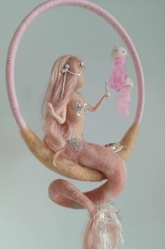 a pink doll sitting on top of a moon with a toy in it's hand