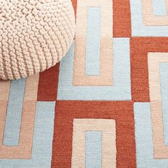 a multicolored area rug on the floor next to a white ball and pillow