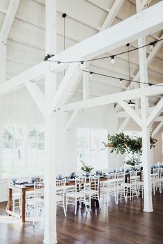 an empty dining room with white chairs and wooden tables set up for a formal function